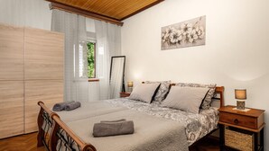 Ein Schlafzimmer mit einem Bett, zwei Nachttischen, einem Schrank, einem Fenster mit Vorhängen und einem Wandbild.