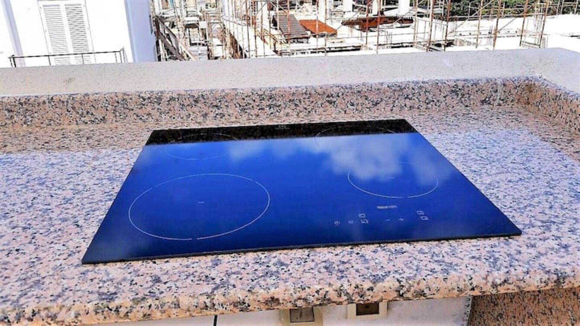 A blue induction cooktop on a granite countertop.
