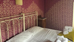 Une chambre à coucher avec un lit, une table de chevet et une lampe fixée au mur.