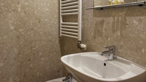 Une salle de bain équipée d’un lavabo sur colonne, d’un bidet, d’un porte-serviettes et d’un miroir.