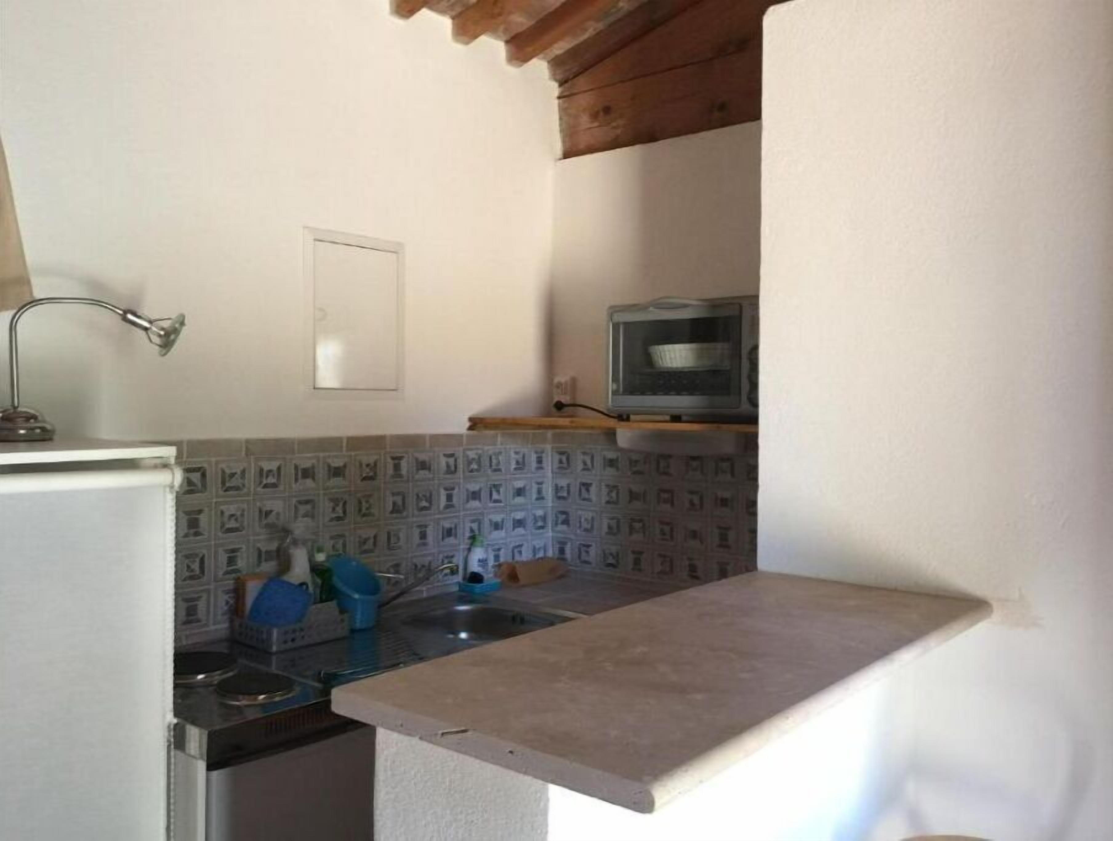 A compact kitchen with a refrigerator, a sink, a microwave, and a small countertop.