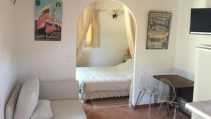 Een slaapkamer met een bed, een stoel, een bureau en een poster aan de muur.