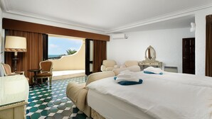 Ein Hotelzimmer mit Bett, zwei Stühlen, einem Tisch, einer Lampe, einem Schminktisch und Blick auf den Ozean.