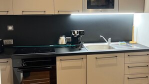 Une cuisine moderne équipée d’un four encastré, d’une machine à café et d’un évier en acier inoxydable.