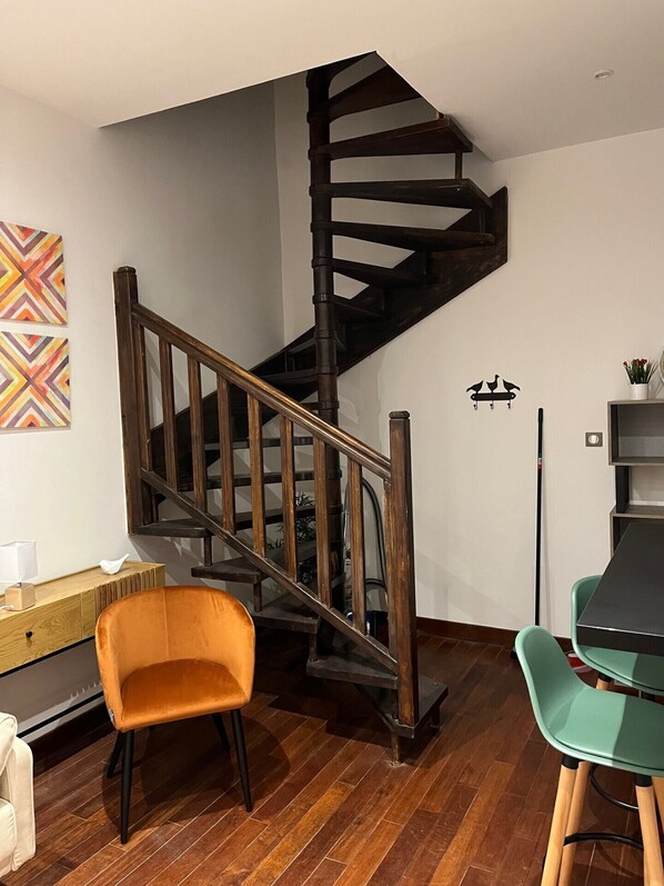 Un intérieur moderne avec un escalier en colimaçon, un plancher en bois et un coin repas équipé de deux chaises.