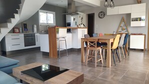 A modern kitchen with white cabinets, a built-in oven, and a dining area with a wooden table and colorful chairs. - Quiet house in Provence (Saint-Cannat)