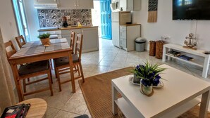 Ett kompakt bostadsutrymme med en matplats, ett kök och en TV som är monterad på väggen.