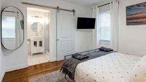 A bedroom with a bed, a TV, a mirror, and a bathroom with a sink and toilet. - This place is peaceful  to stay in, Relax and enjoy. (Greenville)