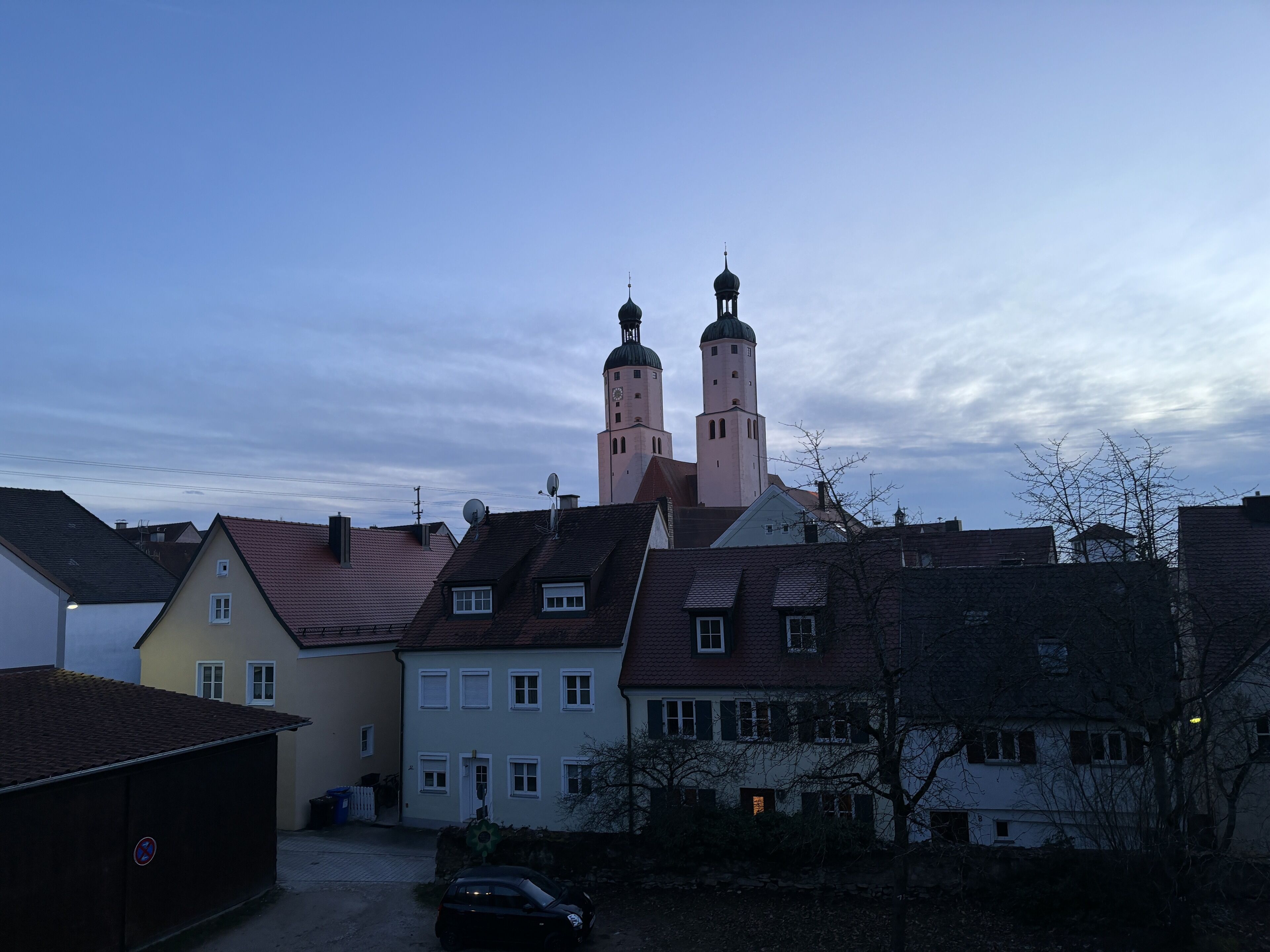 A town with a prominent church featuring two towers and a clock.