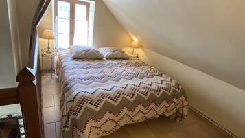 A bedroom with a bed, a nightstand, a lamp, and a window.