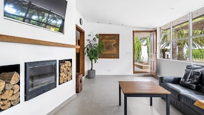 Un salon moderne avec une cheminée, un téléviseur et une grande fenêtre donnant sur des palmiers.