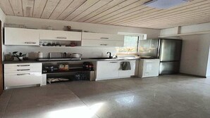 A modern kitchen with white cabinets, a stainless steel refrigerator, and a window providing natural light. - Holiday Home near Baltic Sea & Golf Course (Kołczewo)
