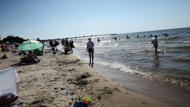 A beach with people walking along the shore and a pier extending into the water. - Holiday Home near Baltic Sea & Golf Course (Kołczewo)
