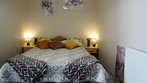 Un letto rifatto con lenzuola fantasia, due lampade ai comodini e un quadro astratto appeso alla parete.