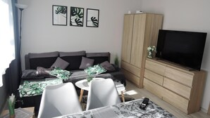 Un soggiorno moderno con un divano, una televisione, un mobile in legno e un'area pranzo con sedie e un tavolo.