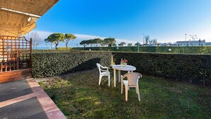 Eine Terrasse mit Tisch und Stühlen, eine hölzerne Pergola und Blick auf Bäume und Gebäude.