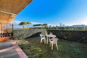 A patio with a table and chairs, a wooden pergola, and a view of trees and buildings. - I Mosaici Apartment by Wonderful Italy (Sirmione)