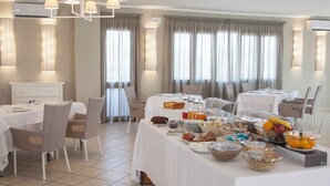 A breakfast buffet setup with various food items and a seating area with chairs and tables. - Hotel Centrale (Sabaudia)