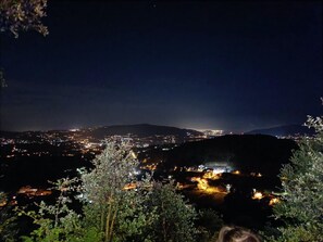 A nighttime view of a city with a prominent hill in the foreground and a valley with illuminated buildings. - Iris Studio Ponte Caldelas to rest peacefully (Ponte Caldelas)