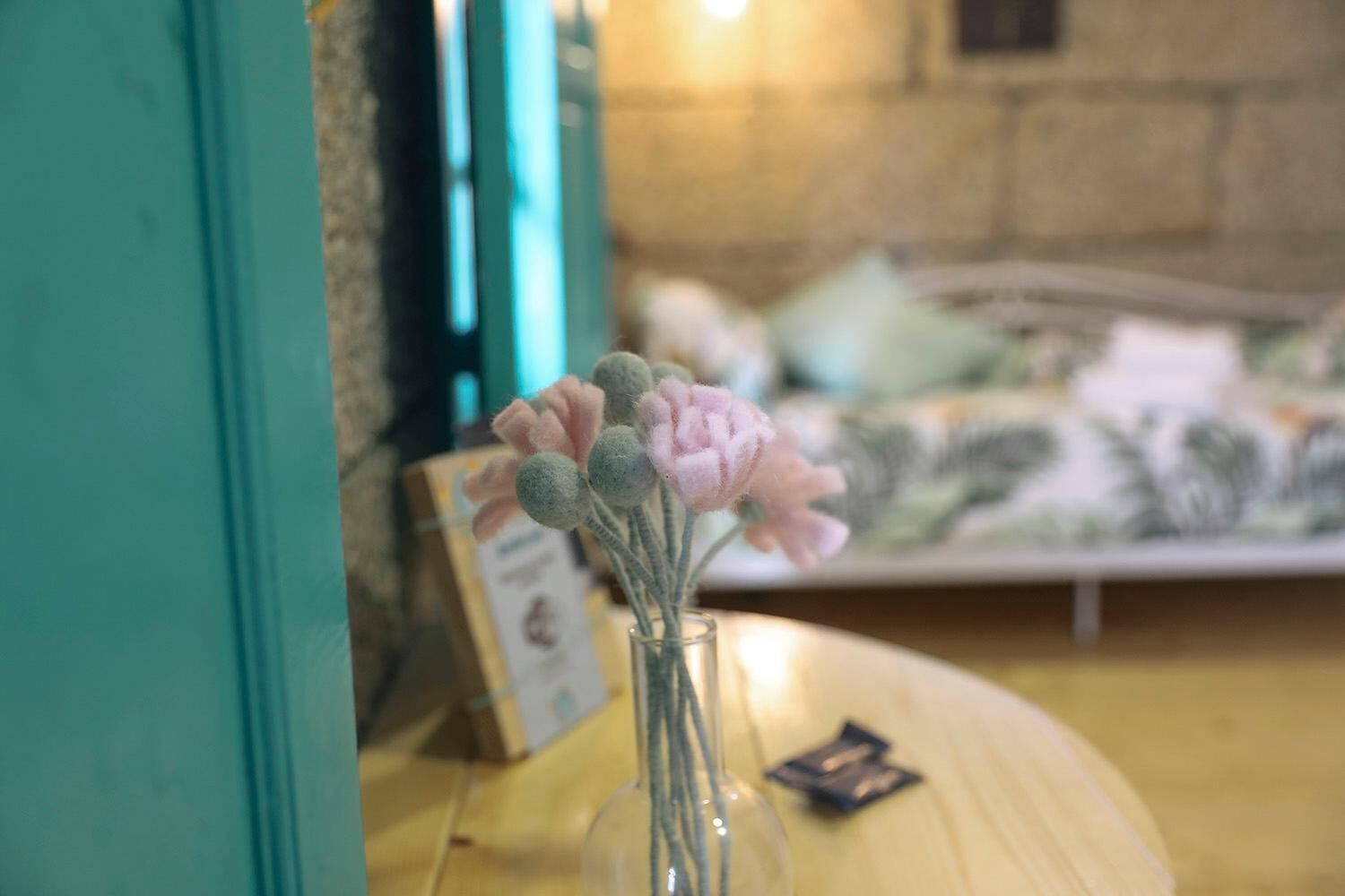 Una cama con un arreglo floral en un jarrón sobre una mesa de madera.