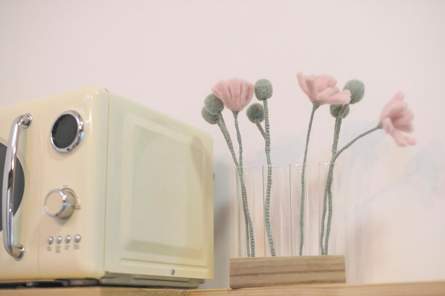 Un four à micro-ondes ancien, posé sur une surface en bois, avec un vase rempli de fleurs roses.