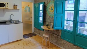A kitchen with a sink, a wooden stool, and teal shutters on the windows. - Dea Dana Studio Ponte Caldelas (Ponte Caldelas)
