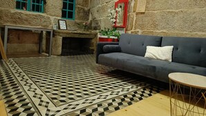 Una habitación acogedora con una pared de piedra, una chimenea, un sofá gris y un suelo con estampado.