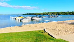 A marina with boats docked, a sandy beach, and a grassy area.
