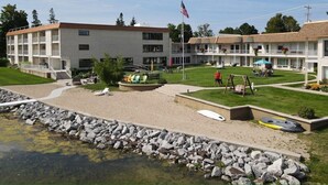 A motel with a swimming pool, outdoor seating, and a flag.