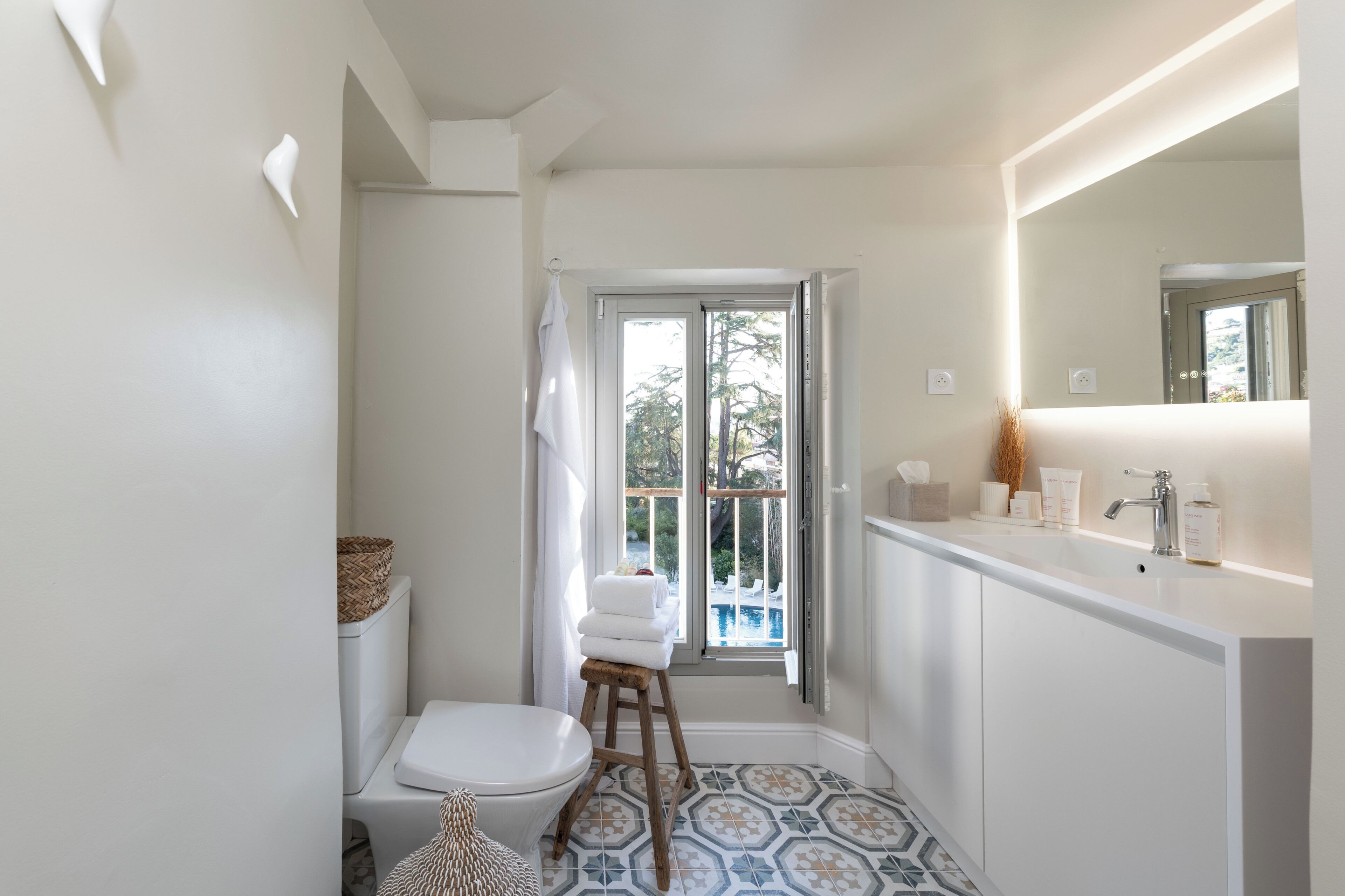A bathroom with a toilet, a sink, a mirror, and a shower area.