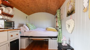 Una stanza accogliente e rustica con un letto, un angolo cottura e un soffitto in legno.