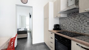 Una cocina moderna con armarios de madera clara, lavavajillas negro y salpicadero de azulejos.