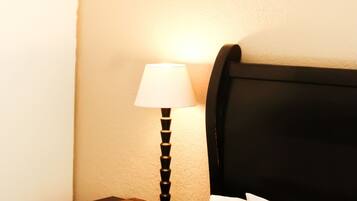 A neatly made bed with white linens, a black headboard, and a bedside table with a lamp and a placemat.