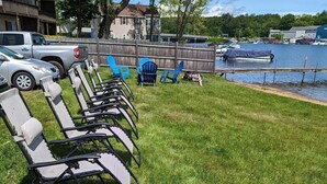 A grassy area with outdoor seating and a dock by a lake.