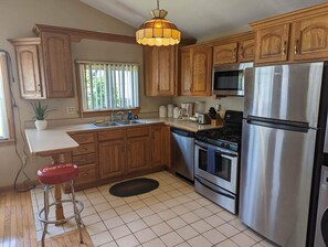A kitchen with wooden cabinets, a stainless steel refrigerator, a stove, and a sink.