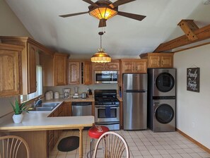 A kitchen with wooden cabinets, stainless steel appliances, a ceiling fan, and a pendant light.