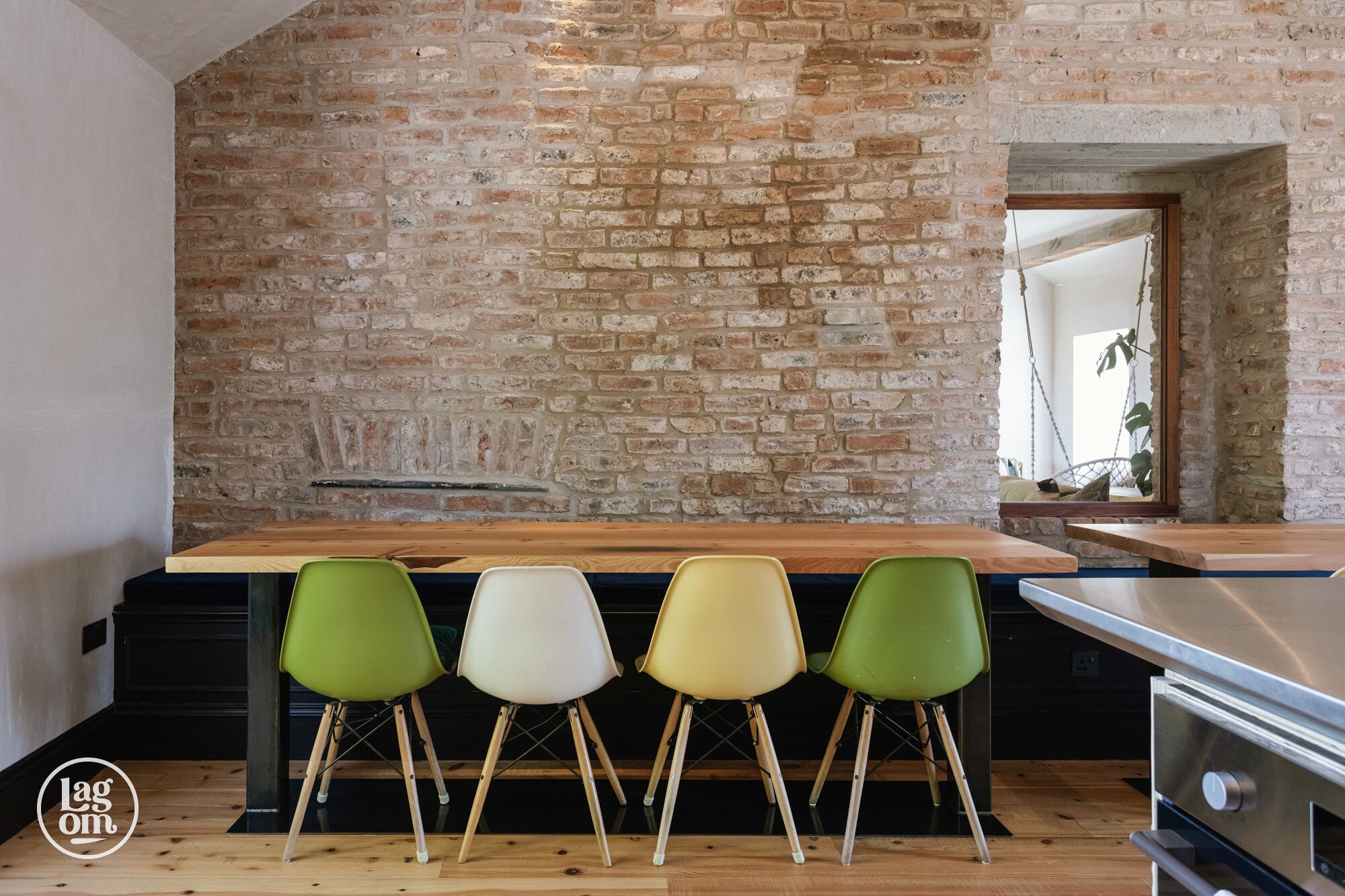 A kitchen with a brick wall, wooden bar counter, and four chairs.