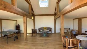 A spacious room with wooden beams, a ping pong table, and a round table with chairs. - Seaside Serenity: Luxury Glamping Getaway - Sleeps 6 (St Peters)