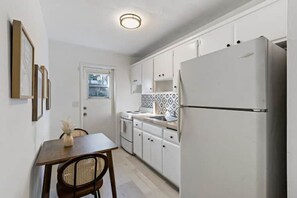 Enjoy cooking in this well-equipped kitchen with a stainless steel refrigerator, dining table, and sink with a window above.