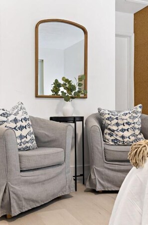Relax in this stylish living room with two comfortable armchairs, a large mirror, and a side table.
