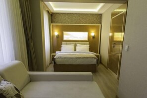 A hotel room with a bed, a bedside table, a nightstand, a sofa, and a wardrobe. - MARS HOTEL (Istanbul)