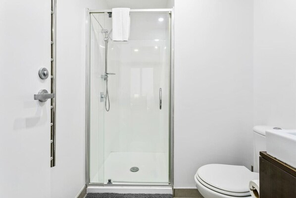 Un baño moderno con ducha acristalada, inodoro y lavabo.