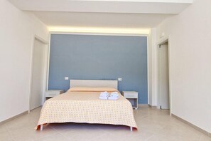 Une chambre à coucher bien rangée, avec un lit, des tables de chevet et une petite table de nuit.