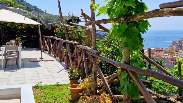 A terrace with a view of the sea, wooden pergola, outdoor seating, and potted plants. - Villa in Lemon Grove With Sea Views & Sea Breeze (Minori)