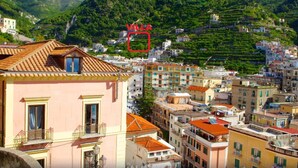 A coastal town with terraced houses and a prominent pink building with a balcony. - Villa in Lemon Grove With Sea Views & Sea Breeze (Minori)