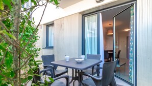 An outdoor dining area with a table and chairs, a view of the interior, and a sliding glass door.