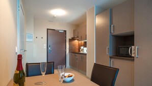 A modern kitchen with a dining table, chairs, a bottle of wine, and a glass.