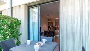 A small outdoor dining area with a table and chairs, a bowl of cookies, and a cup. - Les Sables 504 - Appt avec piscine partagée (Concarneau)