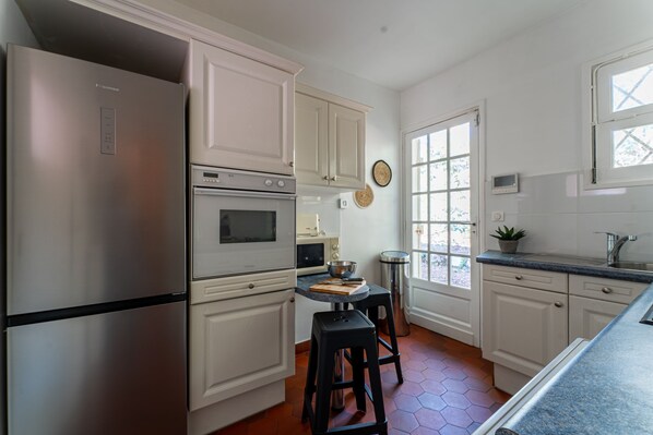 A kitchen with white cabinets, stainless steel appliances, a window, and a potted plant.