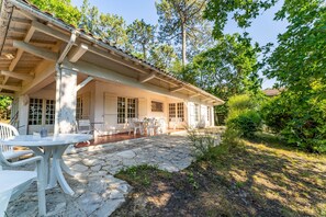 Une maison dotée d’un patio en pierre, d’un espace salon extérieur et d’un porche abrité.